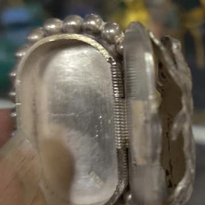 May include: A silver hinged box with a beaded edge and a detailed design. The box is open and the inside is visible.