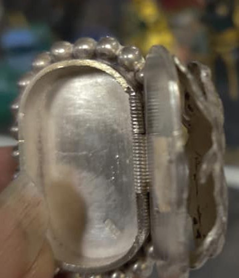 May include: A silver hinged box with a beaded edge and a detailed design. The box is open and the inside is visible.