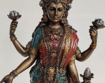 May include: A multi-armed bronze statue of a Hindu goddess with a golden crown, intricate jewelry, and a colorful sari. She holds a lotus flower in each hand and a pot in one hand.