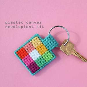 Peut inclure: Un porte-clés en point d'aiguille sur toile en plastique coloré avec un motif arc-en-ciel. Le porte-clés est attaché à un anneau de clé argenté et une clé dorée.