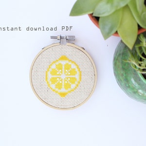 May include: A close-up of a completed cross-stitch embroidery project in a wooden hoop. The design is a yellow lemon with a white centre. The text "instant download PDF" is visible at the top of the image.
