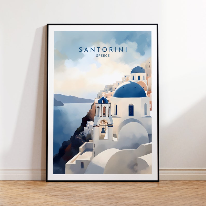 Puede incluir: Un p&oacute;ster enmarcado que representa Santorini, Grecia, en un estilo de acuarela. La imagen muestra edificios blancos con c&uacute;pulas azules, con el texto "SANTORINI GREECE" en la parte superior. La obra de arte est&aacute; ambientada sobre un fondo de mar y cielo azules.