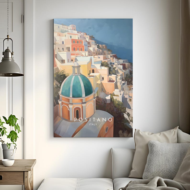May include: A colorful painting of the town of Positano, Italy. The painting features a green-domed church building in the foreground, with a hillside of colorful buildings behind it. The text "Positano, Italy" is printed at the bottom of the painting.