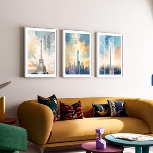 May include: Three framed watercolor paintings of cityscapes. The leftmost painting features the Eiffel Tower in Paris, the middle painting features the New York City skyline, and the rightmost painting features the Burj Khalifa in Dubai.