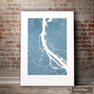 Op de afbeelding: Een blauwe en witte kaartprint van Riga, Letland. De kaart is gedrukt op een witte achtergrond met de stadsnaam "RIGA" in zwart onderaan. De kleur van de kaart wordt beschreven als "Glacier Blue".