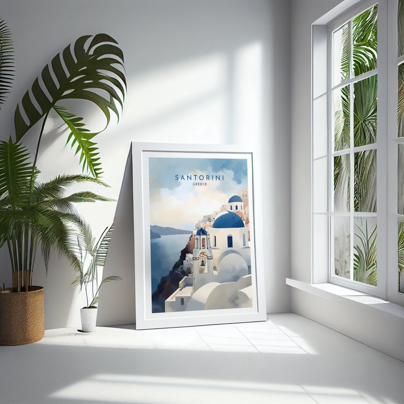 Puede incluir: Una impresi&oacute;n art&iacute;stica enmarcada que representa Santorini, Grecia, en estilo acuarela. La obra muestra edificios blancos con c&uacute;pulas azules en un acantilado con vistas al mar. La impresi&oacute;n est&aacute; en un marco blanco, apoyada contra una pared blanca, junto a una ventana y plantas en maceta.