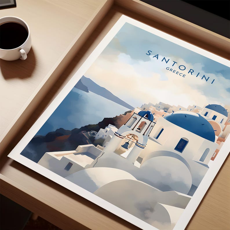 Puede incluir: Una impresi&oacute;n de Santorini, Grecia, con edificios blancos con c&uacute;pulas y detalles azules, sobre un mar y cielo azules. La impresi&oacute;n est&aacute; en una bandeja de madera, con una taza de caf&eacute; en la esquina.