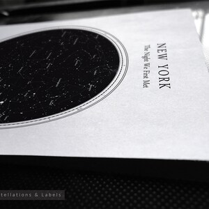 May include: A black and white star map print featuring an oval constellation design. The print includes the text "NEW YORK" and "The Night We First Met". The style is "Constellations & Labels".