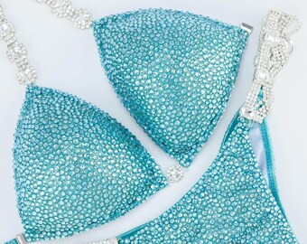 Könnte beinhalten: Ein türkisfarbener Bikini mit Kristallverzierungen. Das Bikinioberteil hat einen Halterneck-Riemen und das Unterteil einen hohen Beinausschnitt.