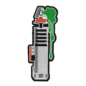 Op de afbeelding: Een geborduurde patch met een lightsaber met een druppelende groene substantie erop. De lightsaber heeft een zwarte handgreep en een zilveren blad.