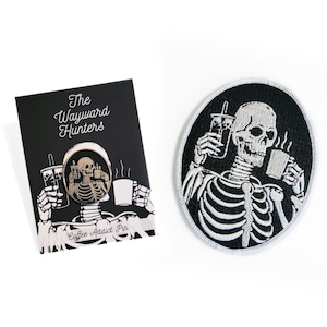 May include: A black and white embroidered patch of a skeleton holding a cup of coffee and a boba tea. The text "The Wayward Hunters" is on a black card with a silver pin of a skeleton holding a cup of coffee and a boba tea. The text "Coffee Addict Pin" is on the card.