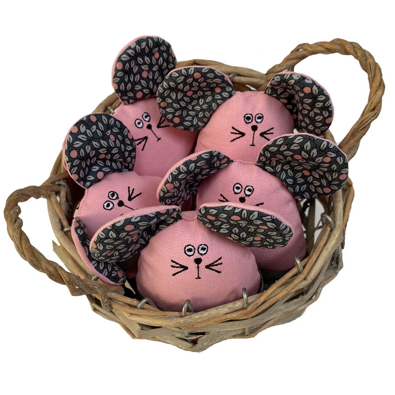 May include: A wicker basket filled with six pink fabric mice. Each mouse has black eyes, a black nose, and black whiskers. The mice have black and white patterned ears.