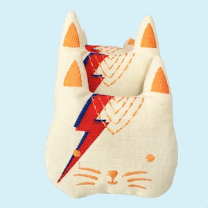 May include: Three white fabric cat toys stacked on top of each other. Each toy has a red, blue, and yellow lightning bolt design and orange embroidered ears.