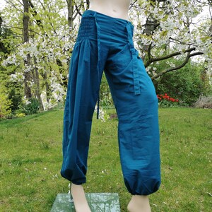 Könnte beinhalten: Tealblaue Baumwollhose mit einem gerafften elastischen Bund und einer Schleife an der Taille.