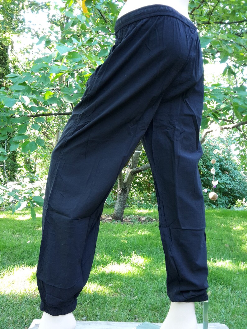 May include: Black cotton pants with a wide leg and a gathered elastic waistband.