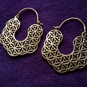 Könnte beinhalten: Ein Paar goldfarbene Creolen mit einem geometrischen Lebensblume-Design.