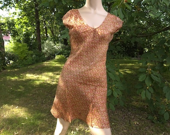 May include: A short-sleeved dress featuring a V-neckline and a repeating floral pattern in shades of rust orange, gold, and cream. The garment has a fitted bodice that transitions into a slightly flared skirt, ending above the knee in length.
