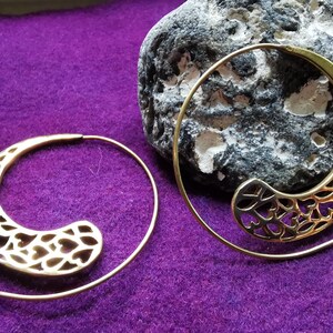 Könnte beinhalten: Ein Paar goldfarbene Spiral-Creolen mit einem herzförmigen Design. Die Ohrringe sind aus Metall und haben ein zartes, filigranes Muster.