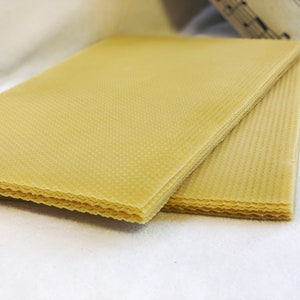 May include: A stack of four sheets of yellow beeswax foundation for beekeeping. The foundation is designed to help bees build their honeycomb.