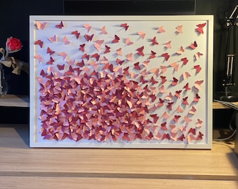 May include: A white framed wall art piece featuring a gradient of pink paper butterflies, with the lightest butterflies at the top and the darkest butterflies at the bottom.