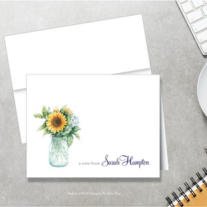 May include: A white card with a blue and black handwritten note that says "a note from Sarah Hampton". The card has a watercolor illustration of a mason jar filled with sunflowers and small white flowers.