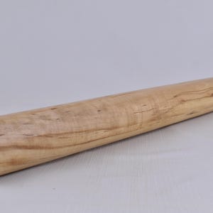 May include: A light-colored wooden rolling pin. The cylindrical pin is made of light-colored wood with visible grain and a rounded end. The rolling pin is approximately 12 inches long.