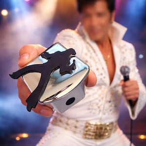 May include: A white ceramic mug with a black handle and the text "But First, Coffee" in a black, handwritten-style font. The mug is on a white surface.