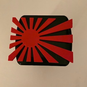 May include: A black and red rising sun emblem on a black background. The emblem is a stylized representation of the sun with 16 rays.