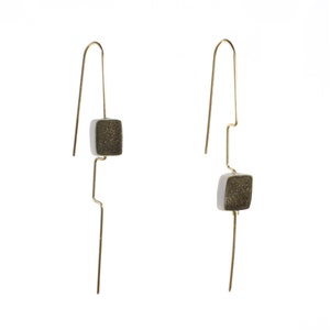 Peut inclure: Une paire de boucles d'oreilles en or avec un pendentif en forme de carré. La pierre est de couleur gris clair avec un motif moucheté gris foncé.