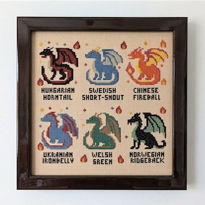 Puede incluir: Obra de arte de punto de cruz enmarcada que representa seis dragones coloridos, cada uno con un diseño y nombre únicos. Los dragones son: Hungarian Horntail, Swedish Short-Snout, Chinese Fireball, Ukrainian Ironbelly, Welsh Green y Norwegian Ridgeback. El marco es de madera oscura.