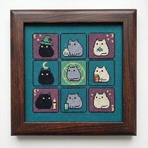 Puede incluir: Obra de arte de punto de cruz en un marco de madera oscura. La obra presenta nueve cuadrados con diferentes diseños de gatos. Los gatos son de varios colores y algunos llevan sombreros o sostienen objetos. El fondo es verde azulado.