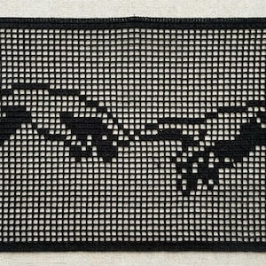 May include: A rectangular black crochet piece featuring a grid-like pattern that forms the silhouette of two reaching hands. The design is created using a filet crochet technique, resulting in a detailed graphic representation of the iconic reaching hands.