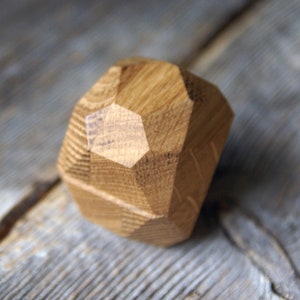 May include: A wooden geometric shape with a natural wood finish. The shape is a dodecahedron, a 12-sided figure.