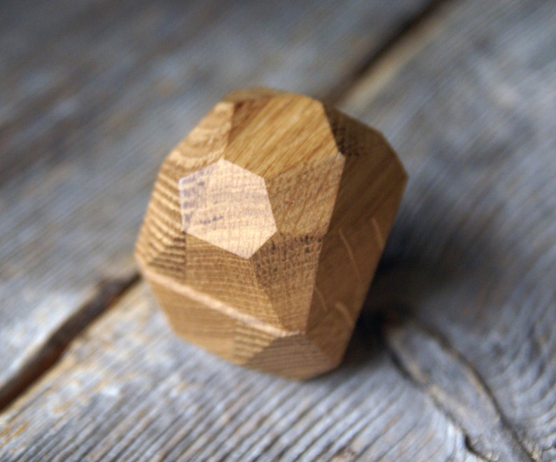 May include: A wooden geometric shape with a natural wood finish. The shape is a dodecahedron, a 12-sided figure.
