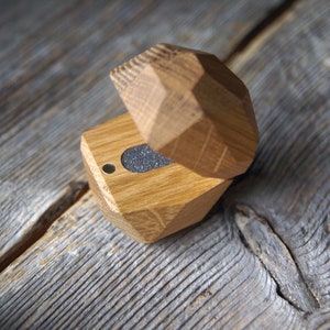 May include: A wooden ring box with a geometric design. The box is open and the inside is lined with gray felt.