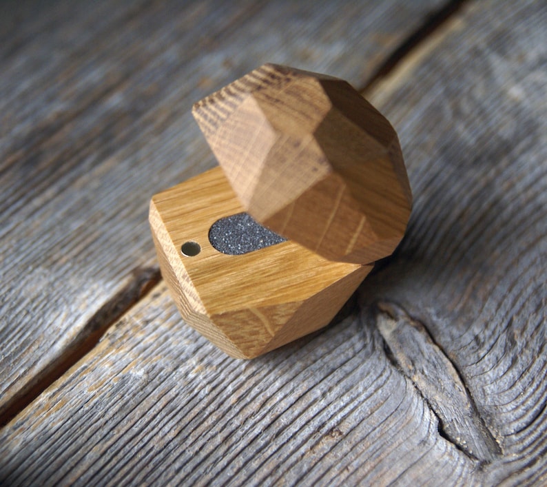 May include: A wooden ring box with a geometric design. The box is open and the inside is lined with gray felt.