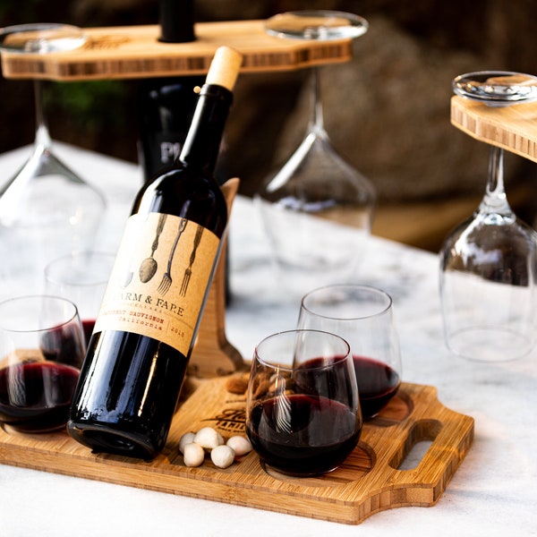 Może przedstawiać: Drewniany stojak na wino z czterema uchwytami na kieliszki i butelką czerwonego wina. Stojak stoi na białym tle z butelką czerwonego wina i czterema kieliszkami czerwonego wina.