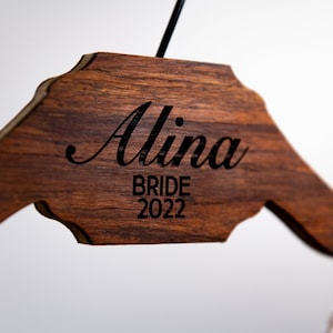 以下が含まれることがあります： 「Alina Bride 2022」と刻まれた木製ハンガー