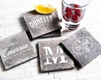 Puede incluir: Cuatro posavasos de piedra gris con letras blancas. Los posavasos presentan los nombres "Donnelly", "Emerson", "Marshall" y "Coleman Family".
