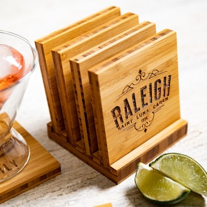 May include: Set of six bamboo coasters with a laser-engraved design featuring the text "Raleigh, Saint Luna Garden, 1996".