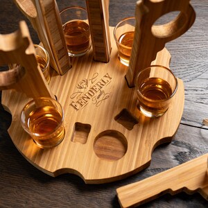Puede incluir: Un soporte de vasos de chupito de madera con seis vasos de chupito llenos de l&iacute;quido &aacute;mbar. El soporte est&aacute; grabado con el texto "Fenderly Family".