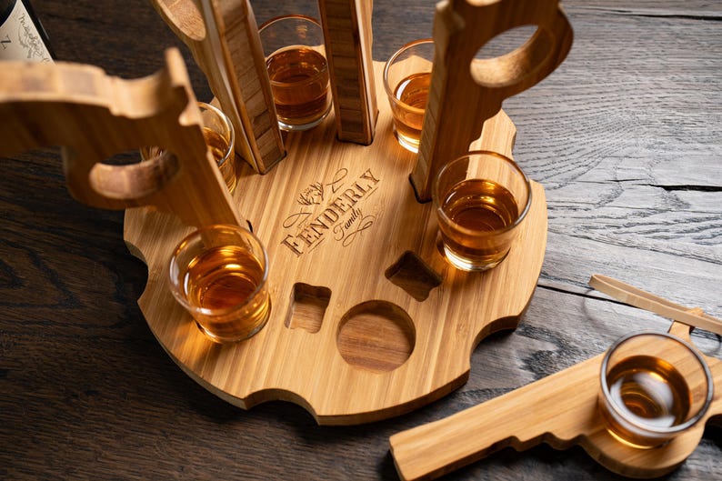 Puede incluir: Un soporte de vasos de chupito de madera con seis vasos de chupito llenos de l&iacute;quido &aacute;mbar. El soporte est&aacute; grabado con el texto "Fenderly Family".