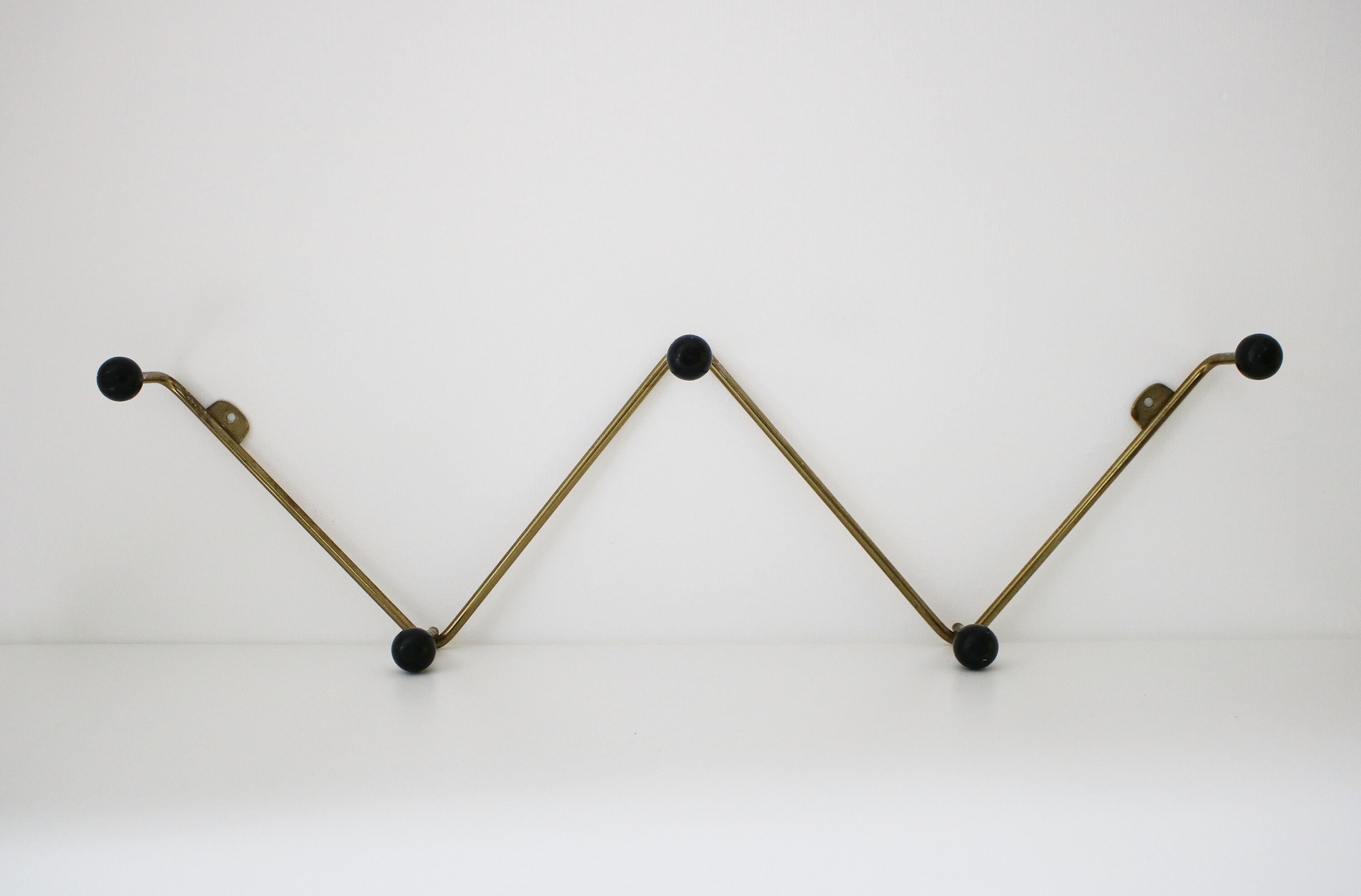 Atomic zigzag coat rack in gilt finish with black wooden bobbles