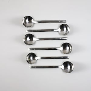 May include: Five silver teaspoons with rounded bowls and long, slender handles.