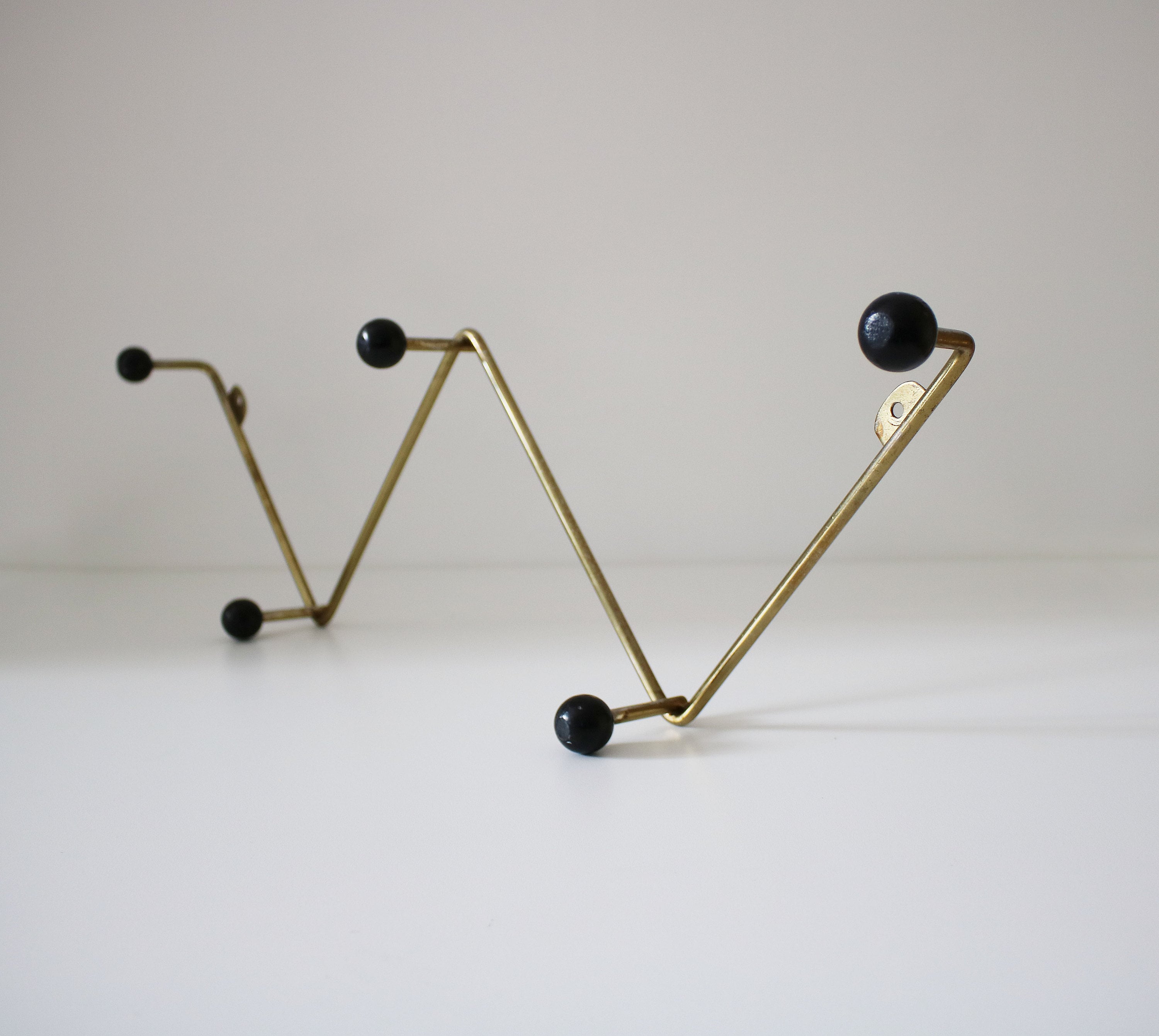 Atomic zigzag coat rack in gilt finish with black wooden bobbles