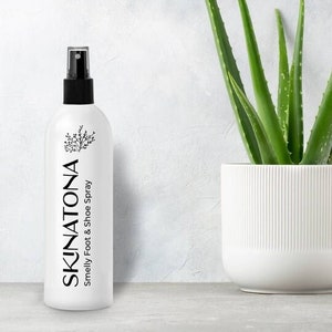 May include: White plastic bottle with a black spray nozzle and black text that reads "SKINATONA Smelly Foot & Shoe Spray".