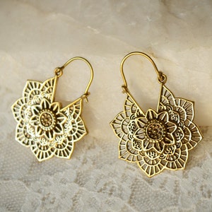 K&ouml;nnte beinhalten: Ein Paar goldfarbene, durchbrochene Ohrringe. Jeder Ohrring hat ein florales Design mit komplizierten Details. Die Ohrringe haben einen Hakenverschluss und werden auf einer wei&szlig;en, strukturierten Oberfl&auml;che pr&auml;sentiert.