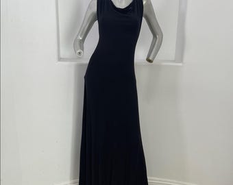 May include: A sleeveless, floor-length black dress with a cowl neckline. The dress has a fitted bodice and a flowing skirt with a side slit. The dress is displayed on a mannequin against a white background.