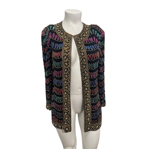 May include: Black open-front jacket with colourful sequin and bead embellishments. The jacket features a gold beaded trim along the edges and neckline. The design includes a pattern of colourful sequins in red, blue, green, and pink.