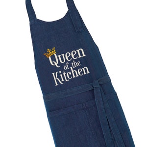 Puede incluir: Un delantal de mezclilla azul con una corona bordada en blanco y el texto "Queen of the Kitchen".